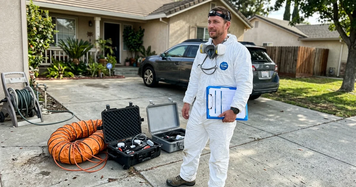 Certified technician holding credential paperwork beside remediation equipment